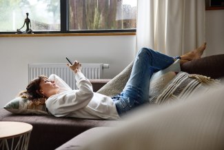 woman is checking her mobilephone while relaxing on her sofa