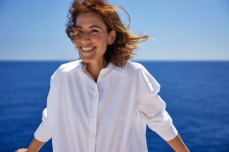 yound woman with white shirt, wind in the hair, feeling the great freedom of travelling on a cruiseship